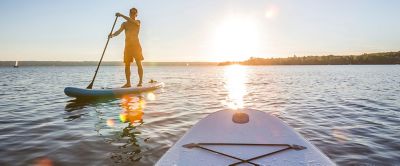 A man is pictured paddling in the sunshine on a stand-up paddleboard.  